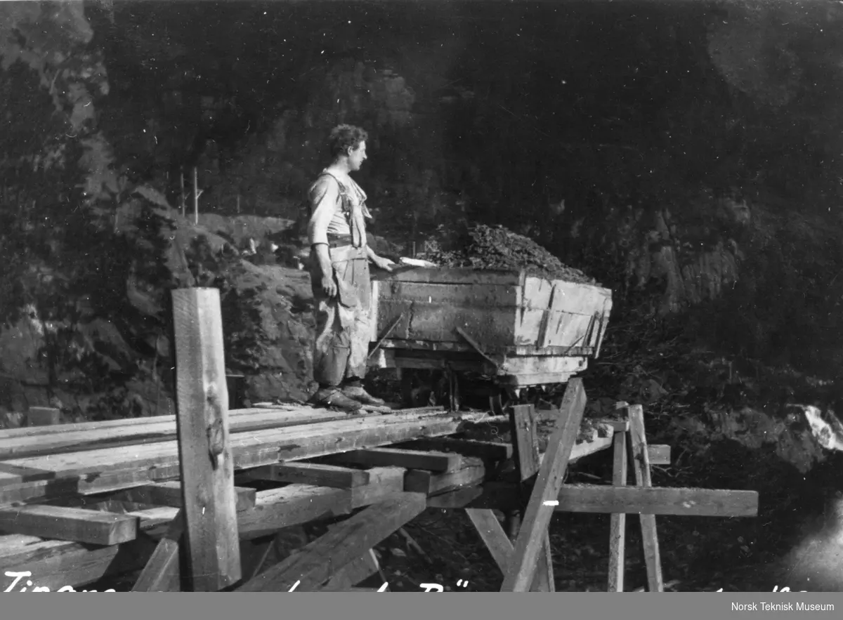 En arbeider står ved siden av en vogn med steinfyllmasse.