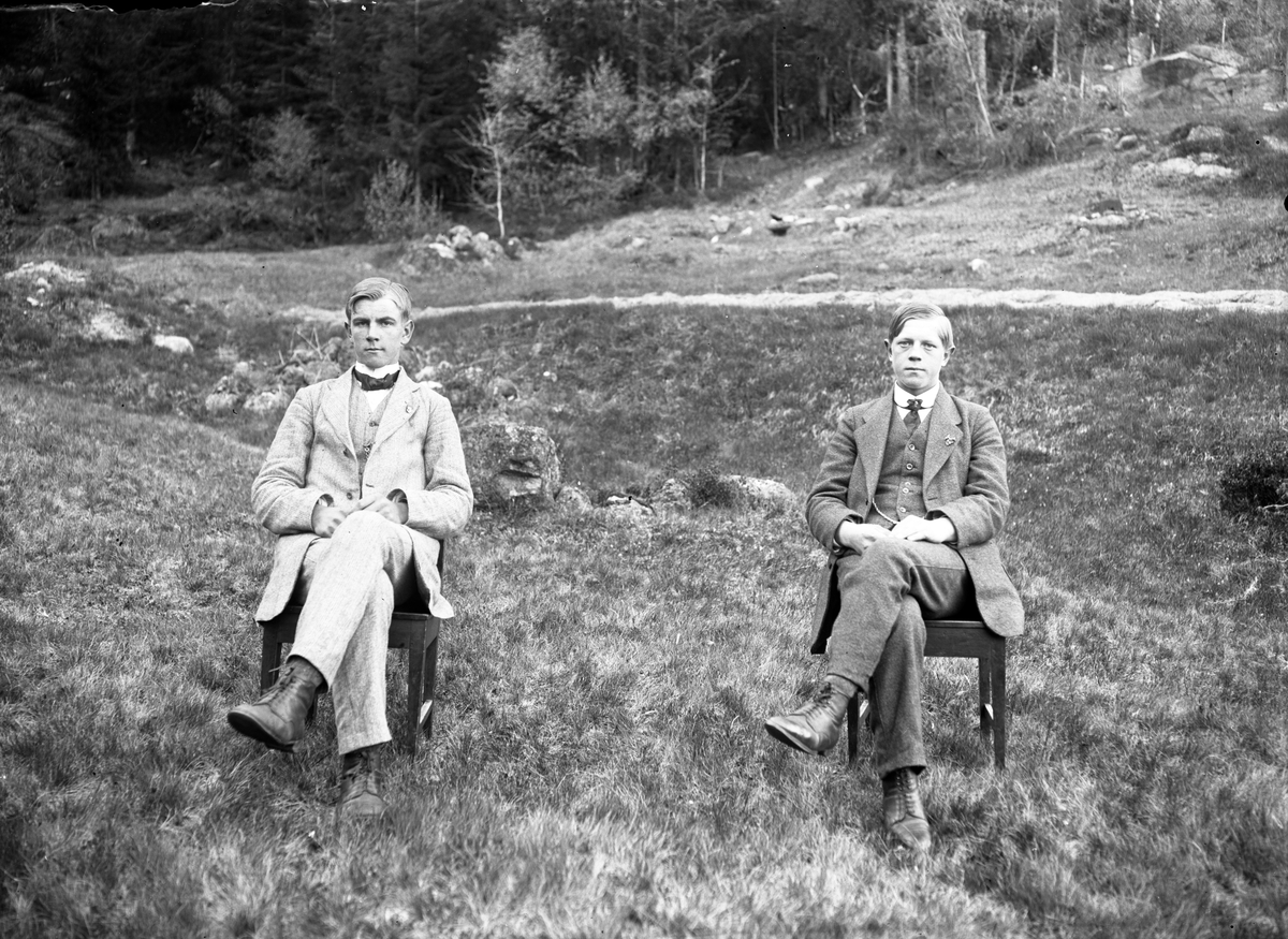 Utendørs portrett av to unge menn på stoler.

Fotosamling etter fotograf og skogsarbeider Ole Romsdalen (f. 23.02.1893).