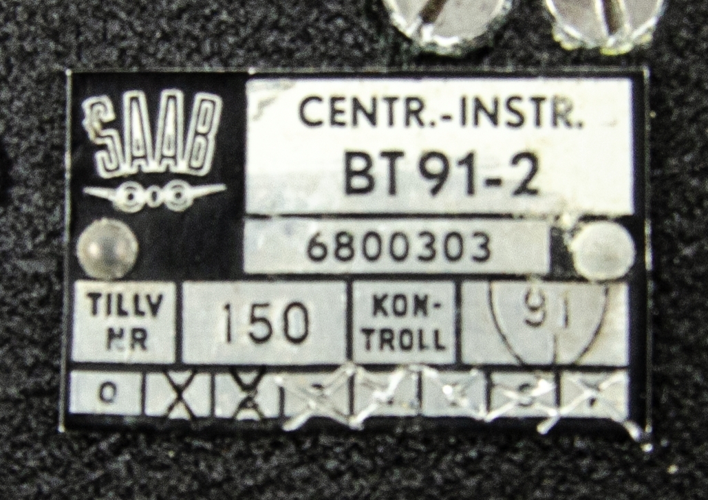 Centralinstrument för bombsikte BT 91-2. Tillhör flygplanstyp A 32 A, Lansen. Tillverkad av metall och hårdplast, svart färg med ett gult och transparent transportskydd. På locket finns en gul skylt med röd text: "ÖMTÅLIGT BEHANDLAS SOM ÄGG" samt en vit klisterlapp: "Nr 150". Tillverkare: SAAB, nummer: 6800303. Till föremålet hör ett kontroll- och följekort.