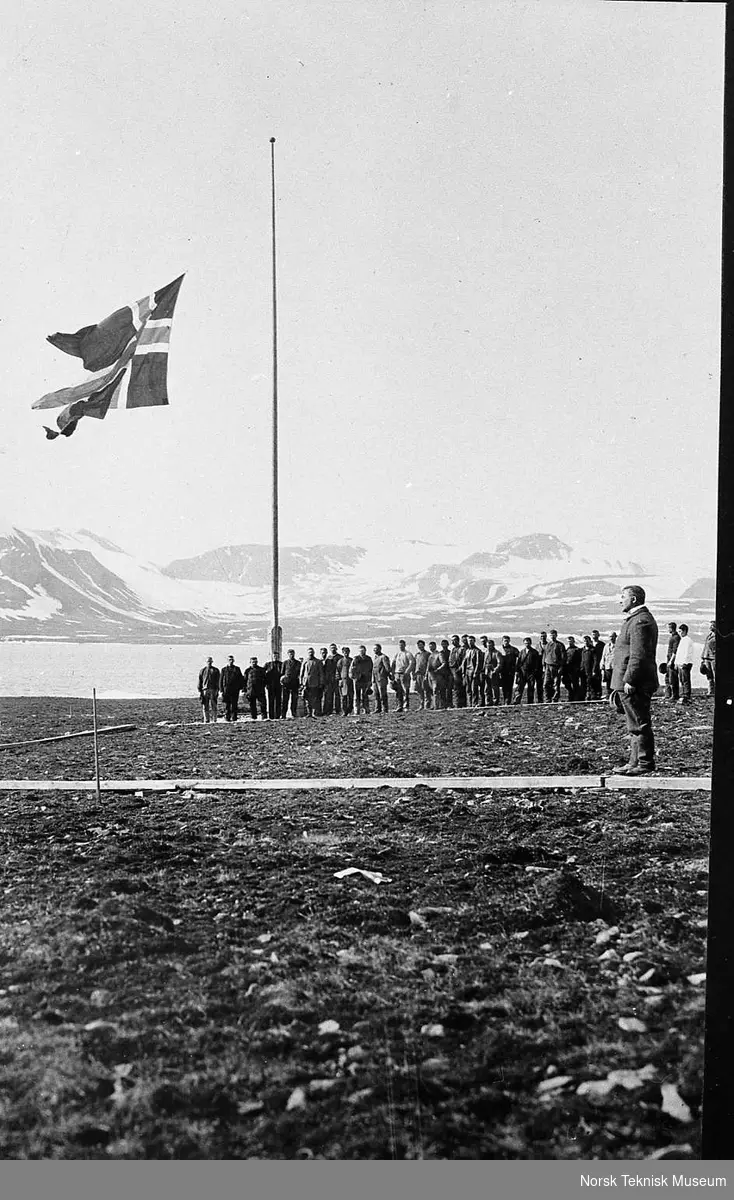 Flagget heises på hvalstasjonen i Green Harbour, Grønfjorden Spitsbergen : telegrafidirektør Thomas Thomassen Heftyes (1860-1921) reise til Svalbard og Ingø i 1911