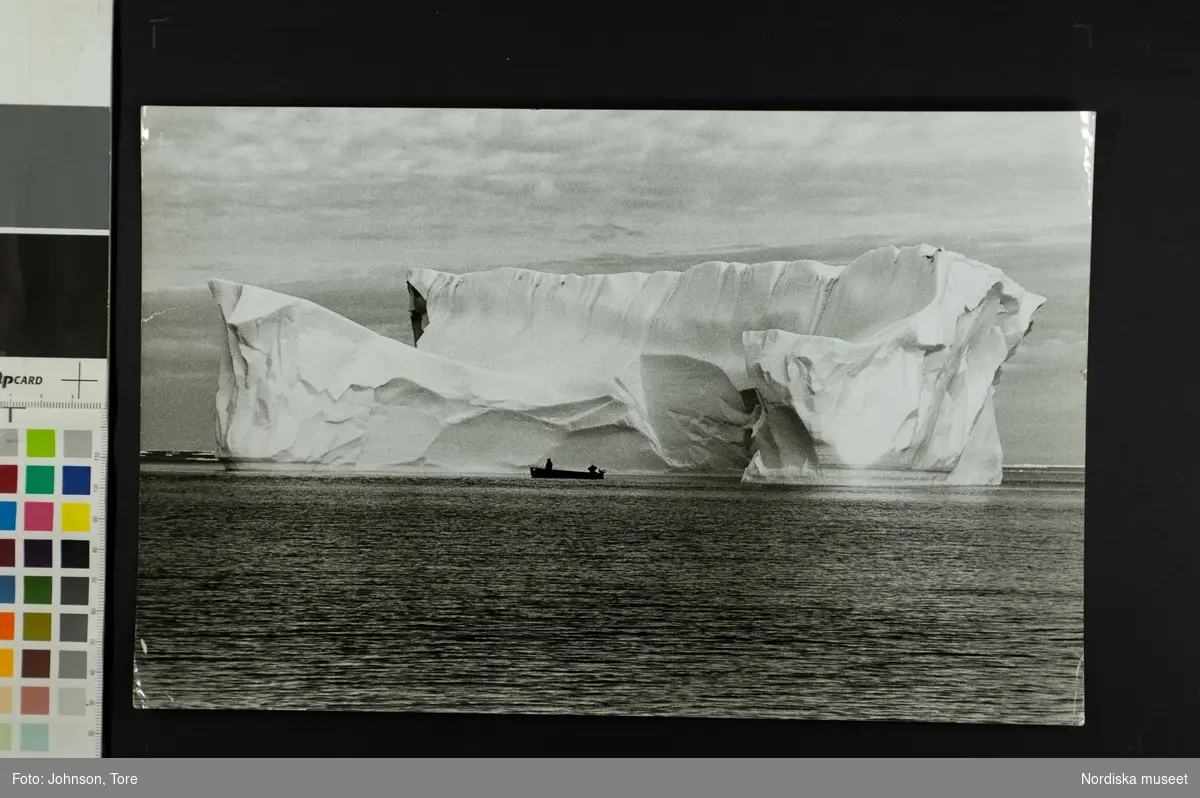 Två människor i båt framför ett isberg. Mellan Baffin Island, Canada och Grönland, skolskjuts.