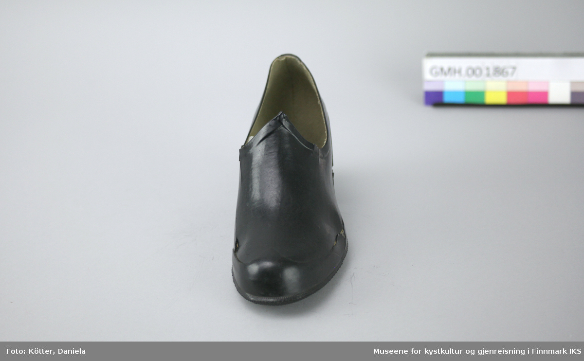 Denne kalosjen er en overtrekkssko av svart gummi. Den er foret med stoff og formen er egnet til damesko med høyere hæl.