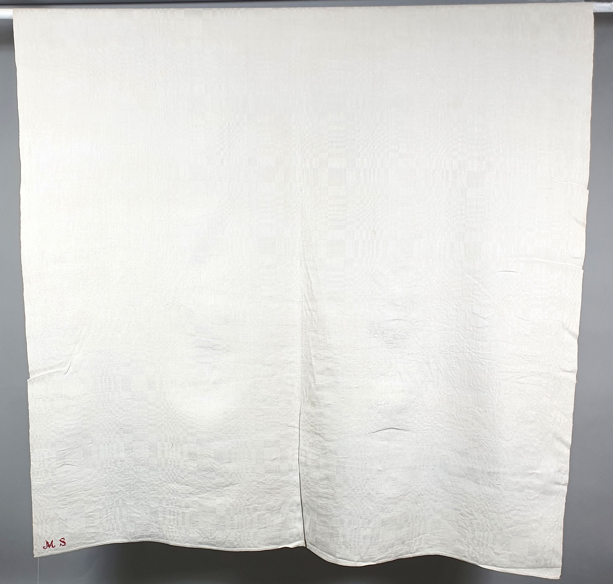 Hvit bordduk av lin, sydd sammen av to, dreielsmønster.