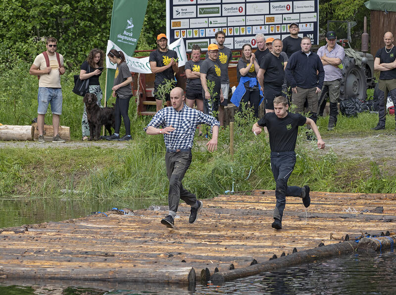 Bildet viser to deltakere i øvelsen bomspringing på tømmerstokker under VM i tømmerfløting 2022