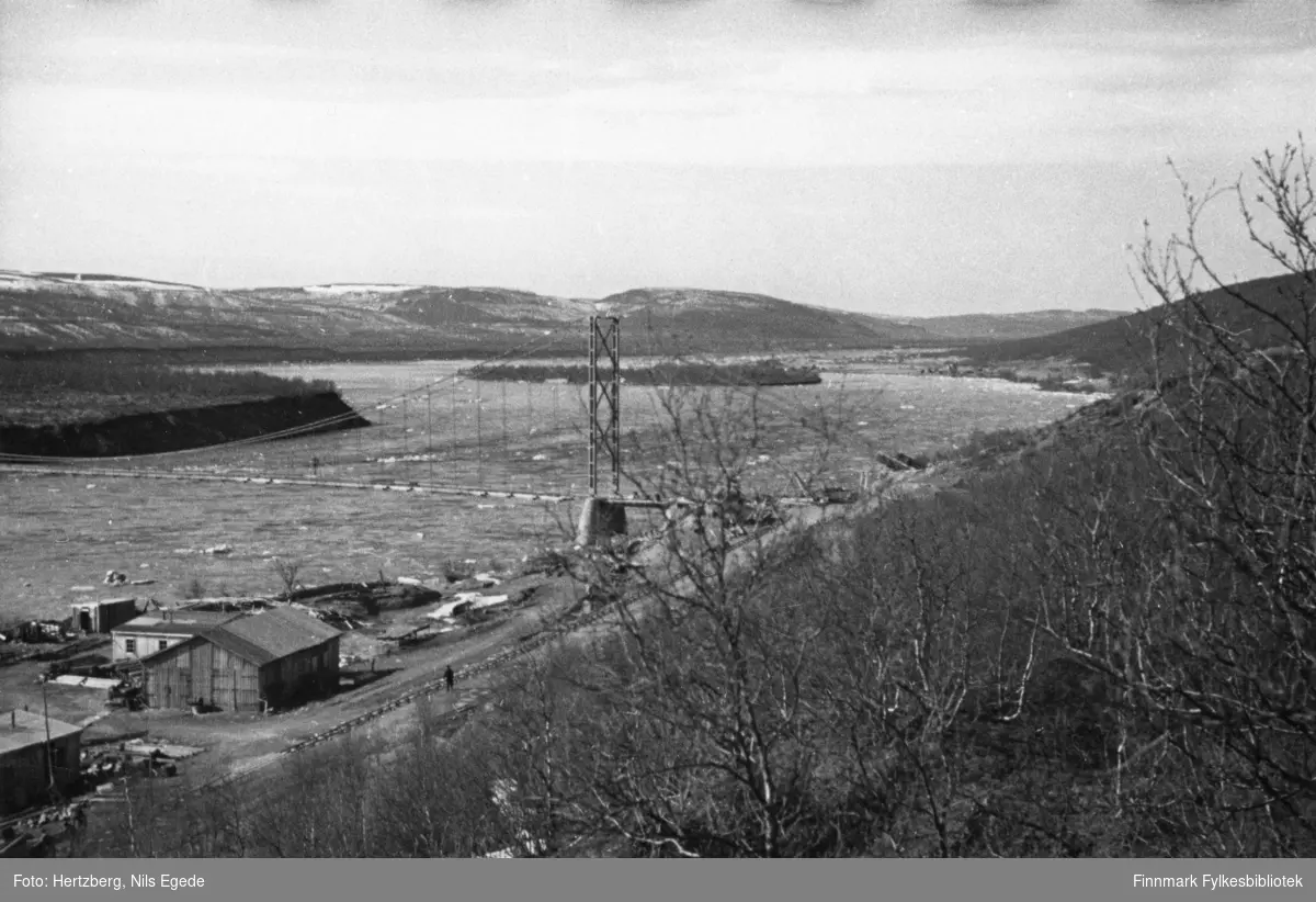Tana bru ble sprengt november 1944. Sommeren 1948 ble Tana bru bygd på nytt. Oversiktsbilde av Tana bru, Tanaelva og litt av brakkeleiren.
