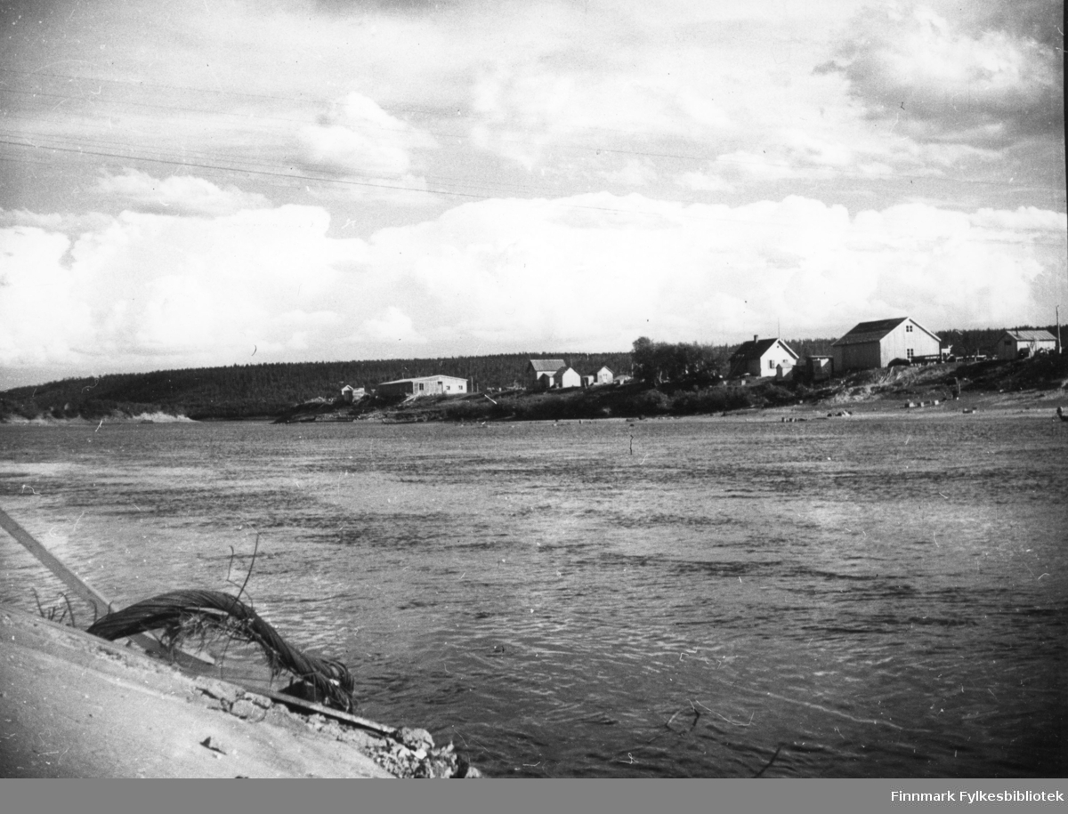 Karasjok. Her ser vi rester etter den sprengte bru til venstre. På andre siden av elva ser man noen hus.