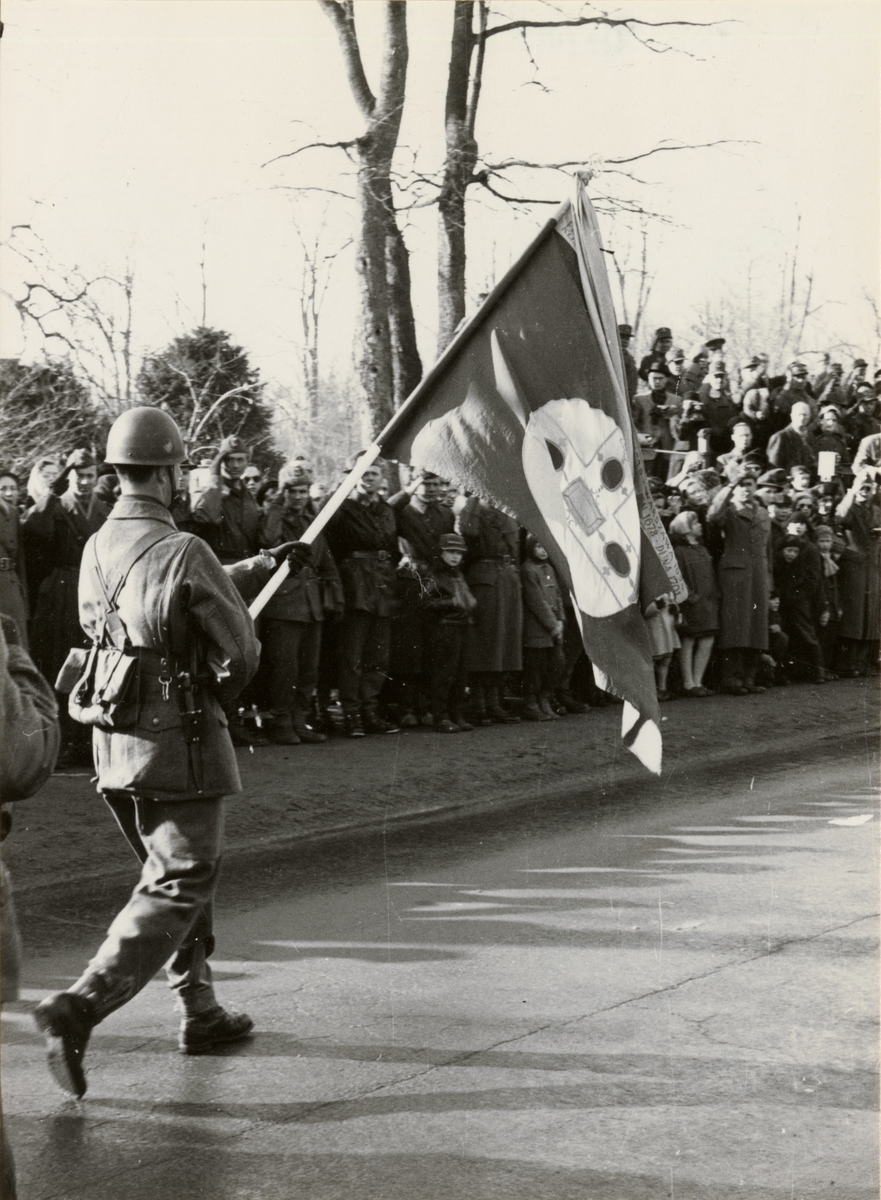 Text i fotoalbum: "Avskedesparaden 10 mars 1957. Kungl. Upplands regementes fana defilerar den 10/3 1957. Fanförare: kapten Hultstrand."
