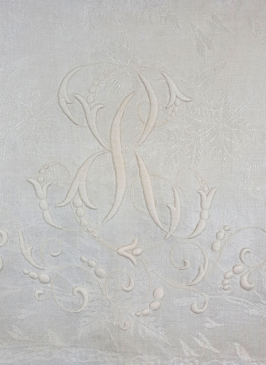 Pyntehåndkle av lin med rosemønster i damaskvev. Brodert monogram og heklet blonde.