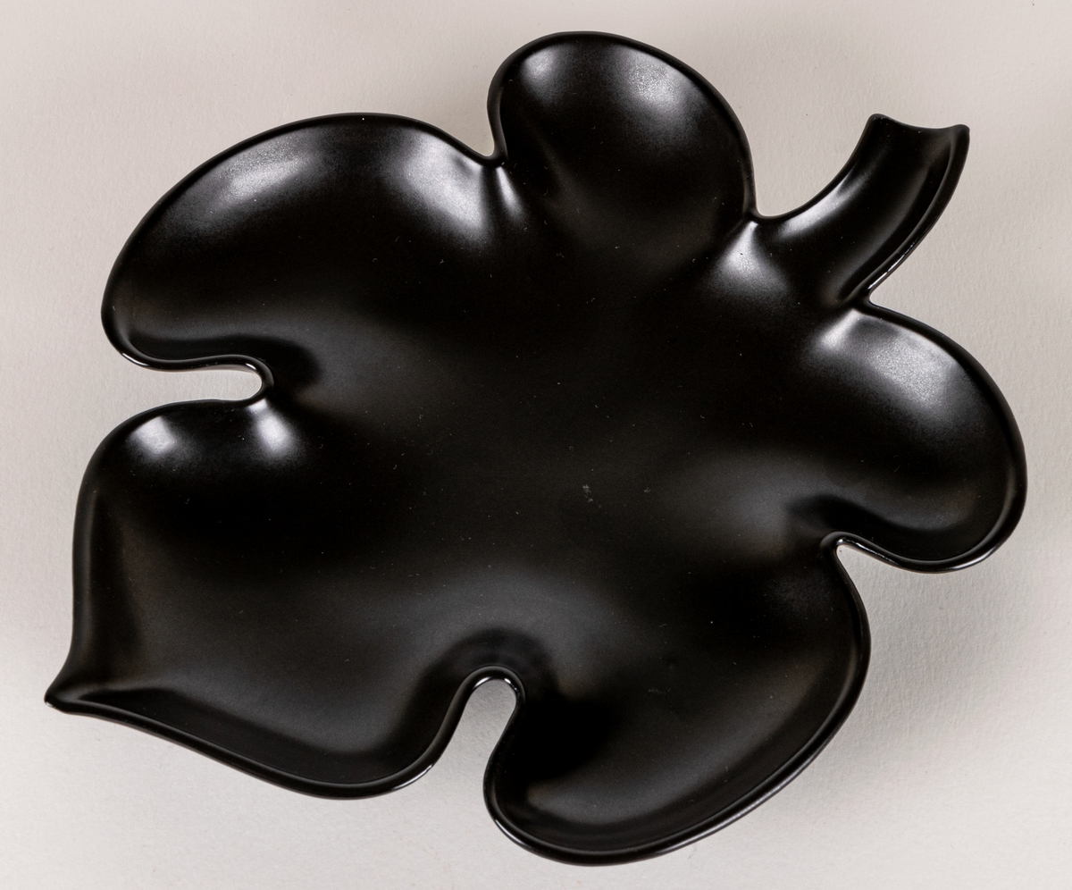 Lövformad skål i flintgods, modell EE, glasyr Mangania. Formgiven av Lillemor Mannerheim 1950.