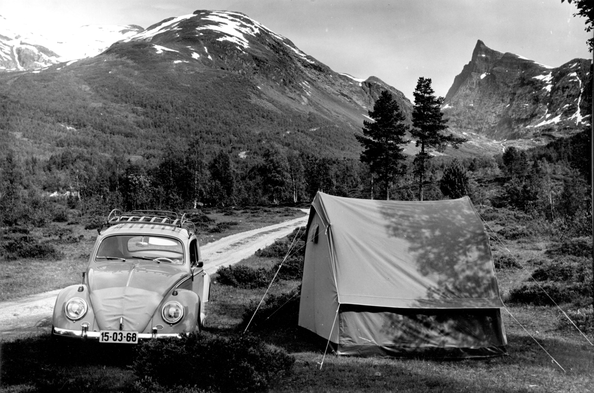 Folkevogn og telt foran ukjent fjellformasjon.