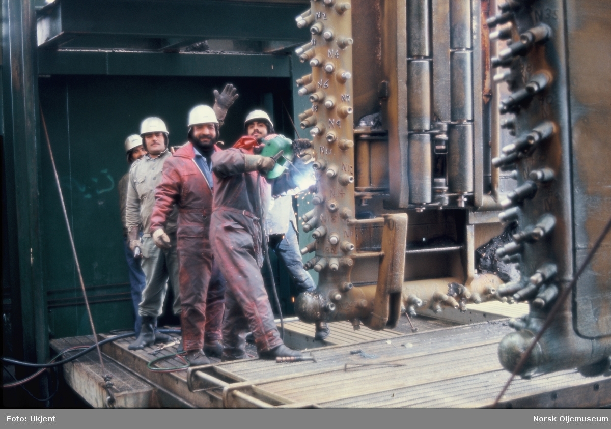 En glad gjeng med arbeidere står bak en mann som sveiser på en installasjon. De to siste bildene er nærbilder av det de arbeider med.