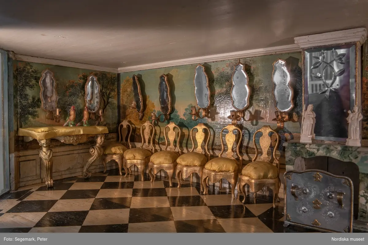 Dockskåp i utställningen "Dockskåp", visad på Nordiska museet 23 dec 1999 - 20 jan 2021.
Det blå kabinettskåpet, år 1760. Skåpet gjordes i ordning för Maria Catharina Falk som var en liten flicka vid mitten av 1700-talet. Det har ärvts och ändrats av andra. På väggarna hänger äkta porträtt av hennes och makens släkt.
I köket står en servis av fajans tillverkad 1746 vid Rörstrands porslinsfabrik. 
NM.0151825
