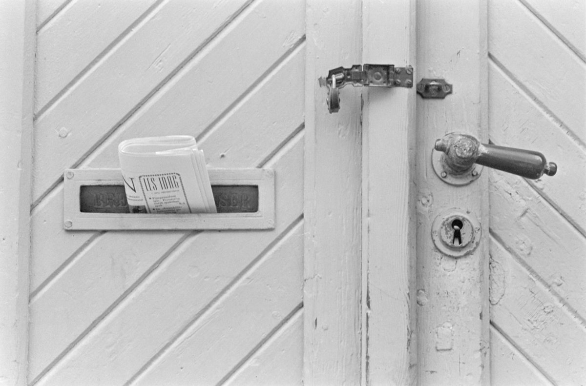 En avis stukket i brevsprekken på en dør.