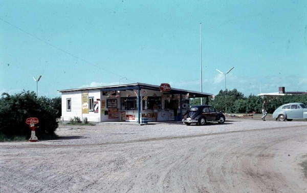 Åstrands kiosk på Skummeslövsstrand. Framför kiosken står en "folkabubbla" och till höger en Volvo PV. Träd och buskar i bakgrunden.
