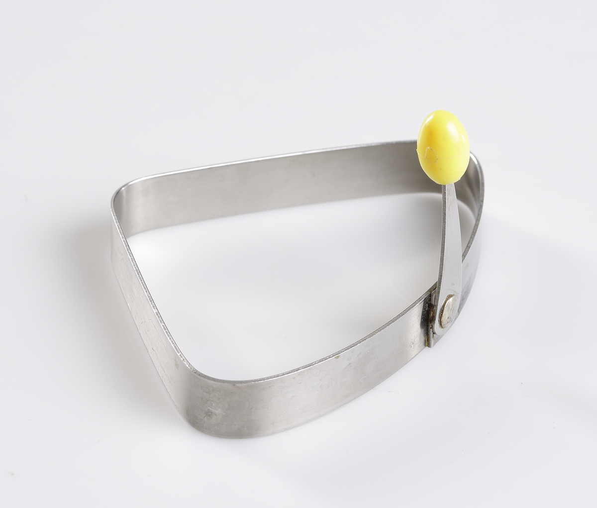 Äggringen "Colomba" i rostfritt stål av märket Nilsjohan. Lyfthandtag i gul plast. Handtaget kan vikas ner längs formens sida.
