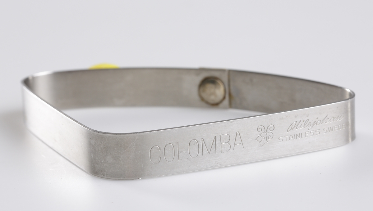 Äggringen "Colomba" i rostfritt stål av märket Nilsjohan. Lyfthandtag i gul plast. Handtaget kan vikas ner längs formens sida.

