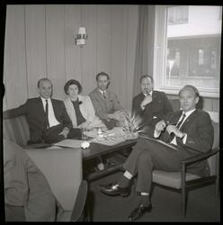 Fotografi av noen kvinner og menn kledd i finklær som sitter