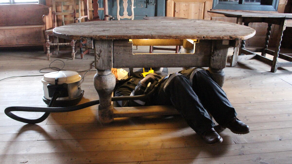Bildet viser en person som støvsuger et bord før flytting.