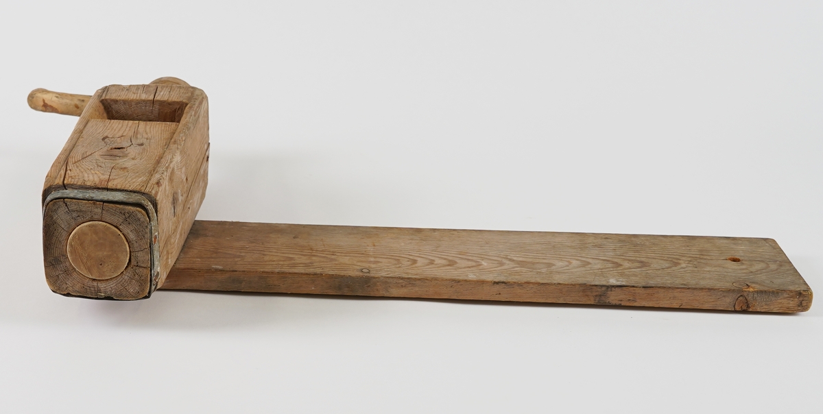 Potetkvern i tre. Består av eit trebrett/plank som underlag, ein sylinder med ei skrue inni, og ei sveiv.