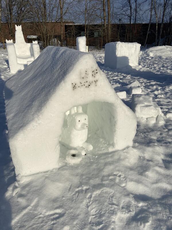 Bildet viser et hundehus og en hund skulpturert av snø
