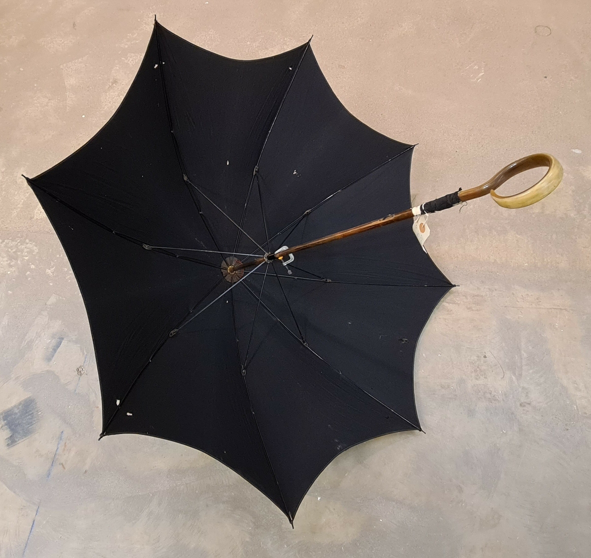 Paraply/parasoll i svart tyg. Krycka i en ring formation.

Ingår i en samling av nio olika parasoller med olika utseende och modell.