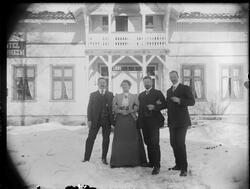 En kvinne og tre menn stående utenfor Løvheim hotell. Alle h