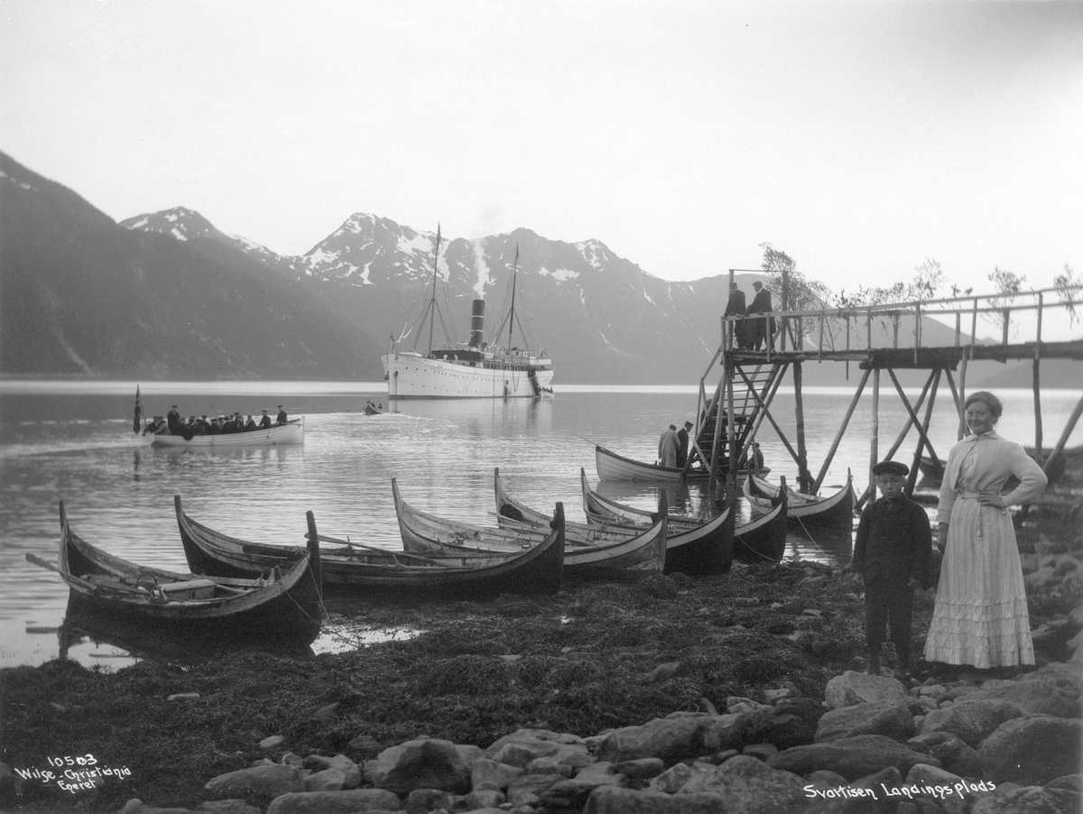 Turister fraktes i småbåter fra passasjerskipet Kong Harald til landingsbryggen på Svartisen. Fotografert i1909.