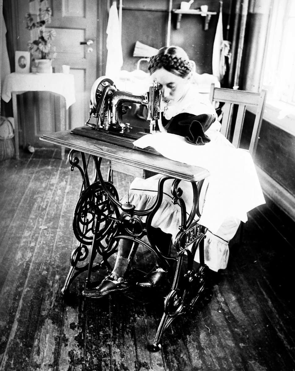 Sterkt funksjonshemmet jente prøver seg ved symaskinen.