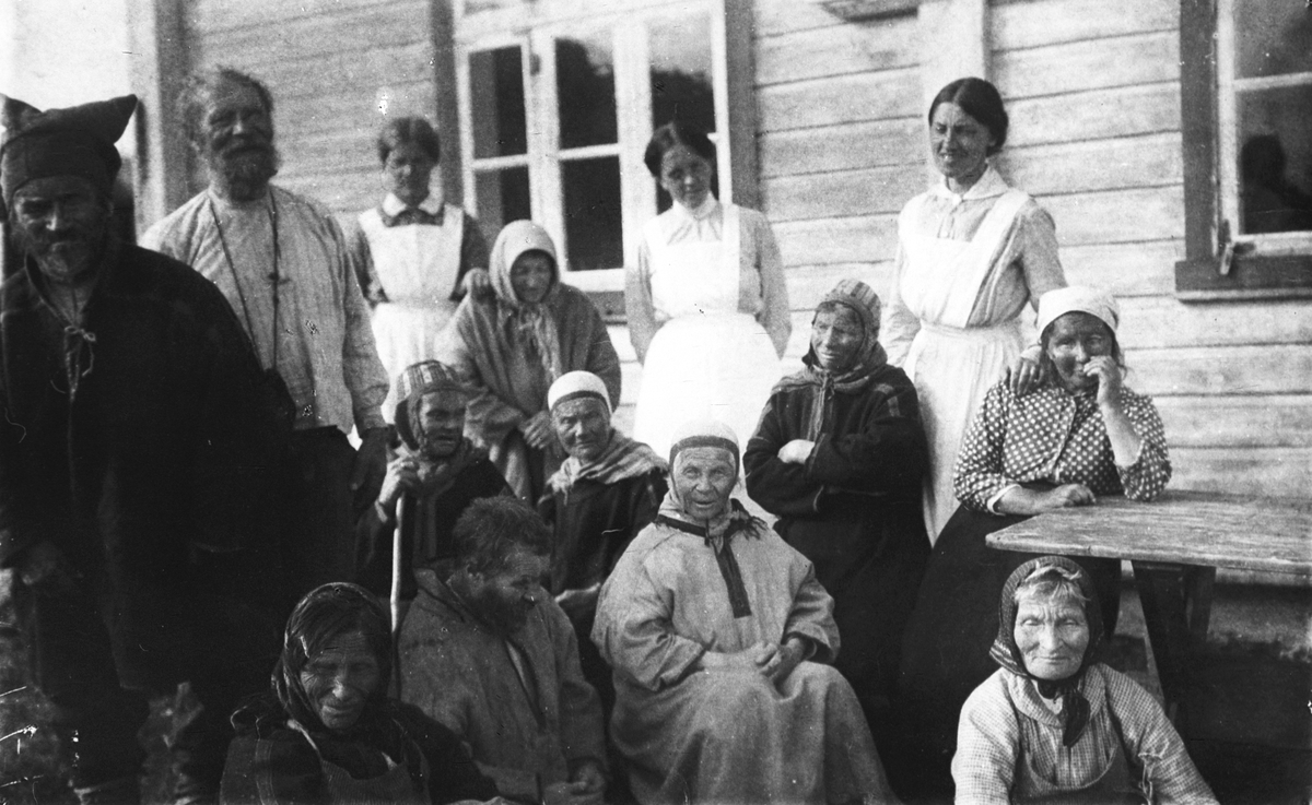 Kvinner og menn sitter sammen med pleiere på Kistrand pleiehjem, med bla fru Herborg Holtan Gundersen. Fotgrafert 1923.
