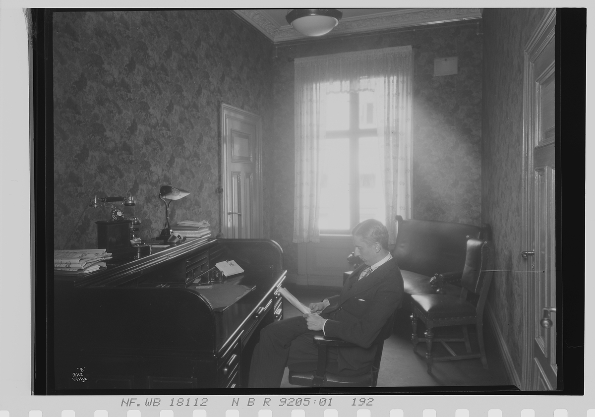 Mann sitter ved kontorpult, Vinmonopolet. Fotografert 1924.
