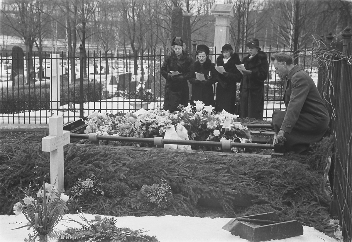 Kvinner som synger ved båren til fru Kiær på Ullern kirkegård. Krans påskrevet Prestegaardens Missionsforening og Bestun Sjømandsmissionsforening. Fotografert 1940.