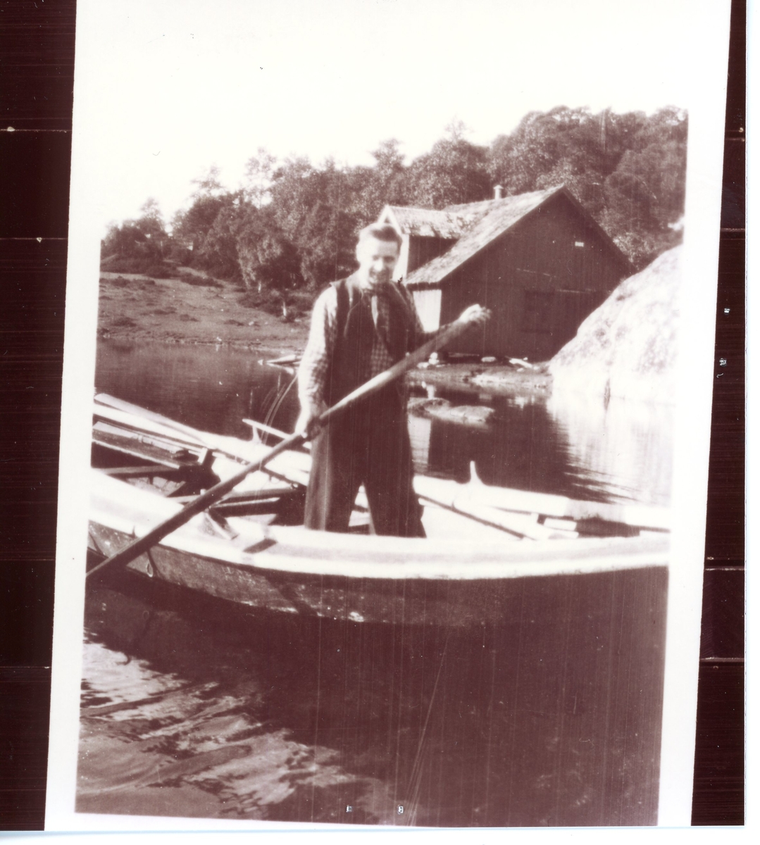 Ingvar Klingenberg stående i en robåt. En brygge i bakgrunn.