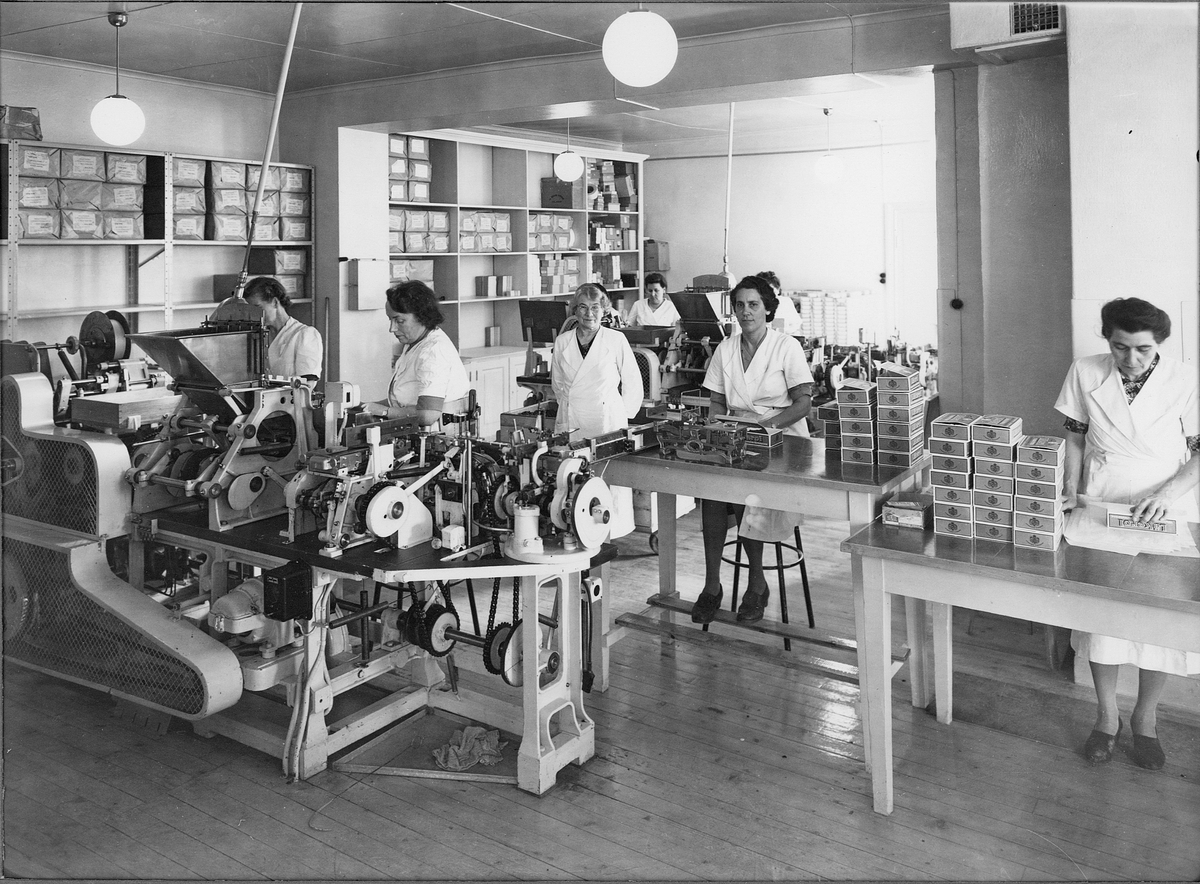 Interiör från Ahlgrens Tekniska fabriks packningsavdelning, Brynäs, Gävle, 1946. Kvinnor arbetar vid den första automatiska packningsmaskinen, som togs i bruk i början av 1940-talet.