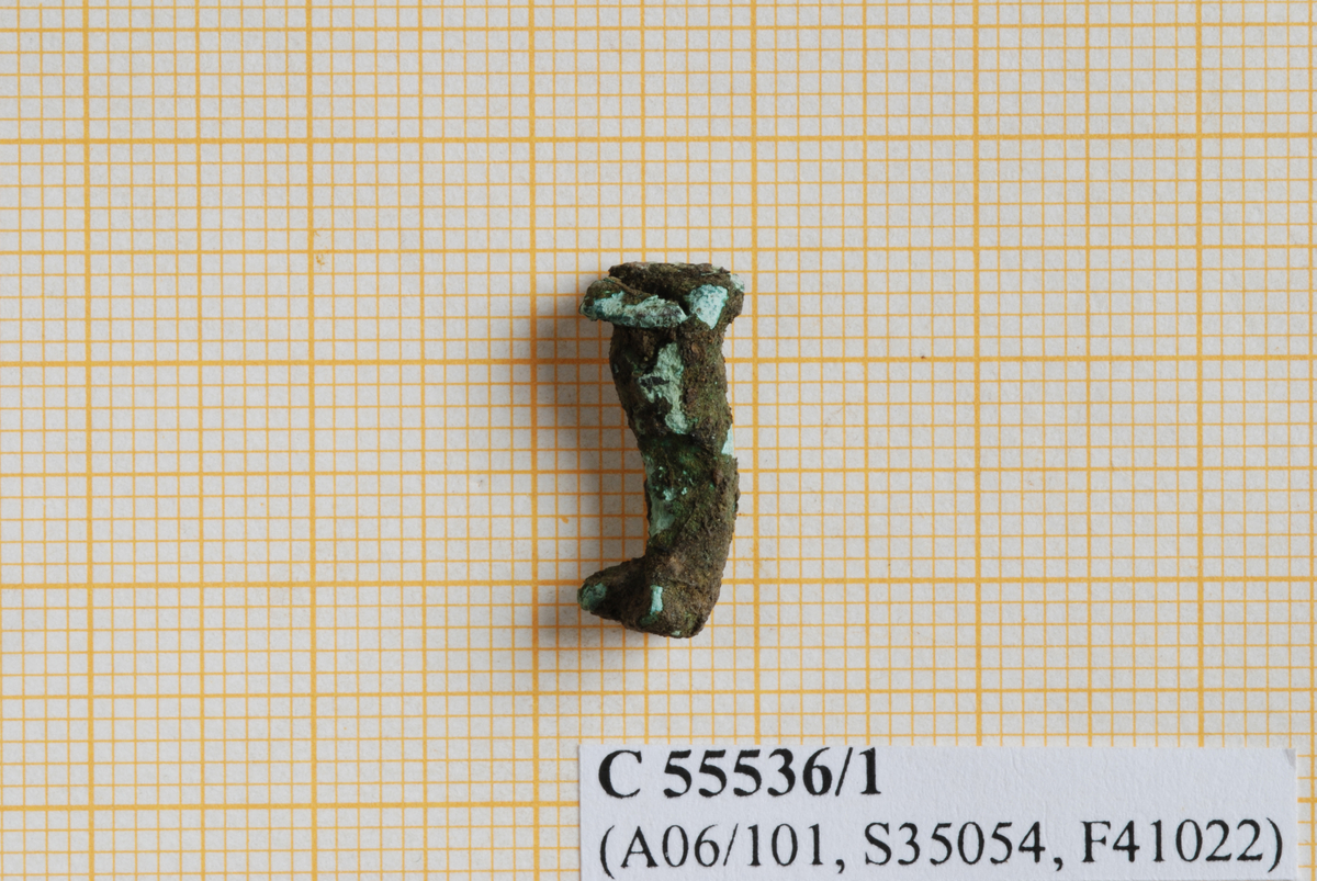 1 fragment av bronse/kopperlegering, muligens del av nagle. Fragmentet har form som en stilk med flate skiver i hver ende. Den ene enden er noe bøyd. Mangler.