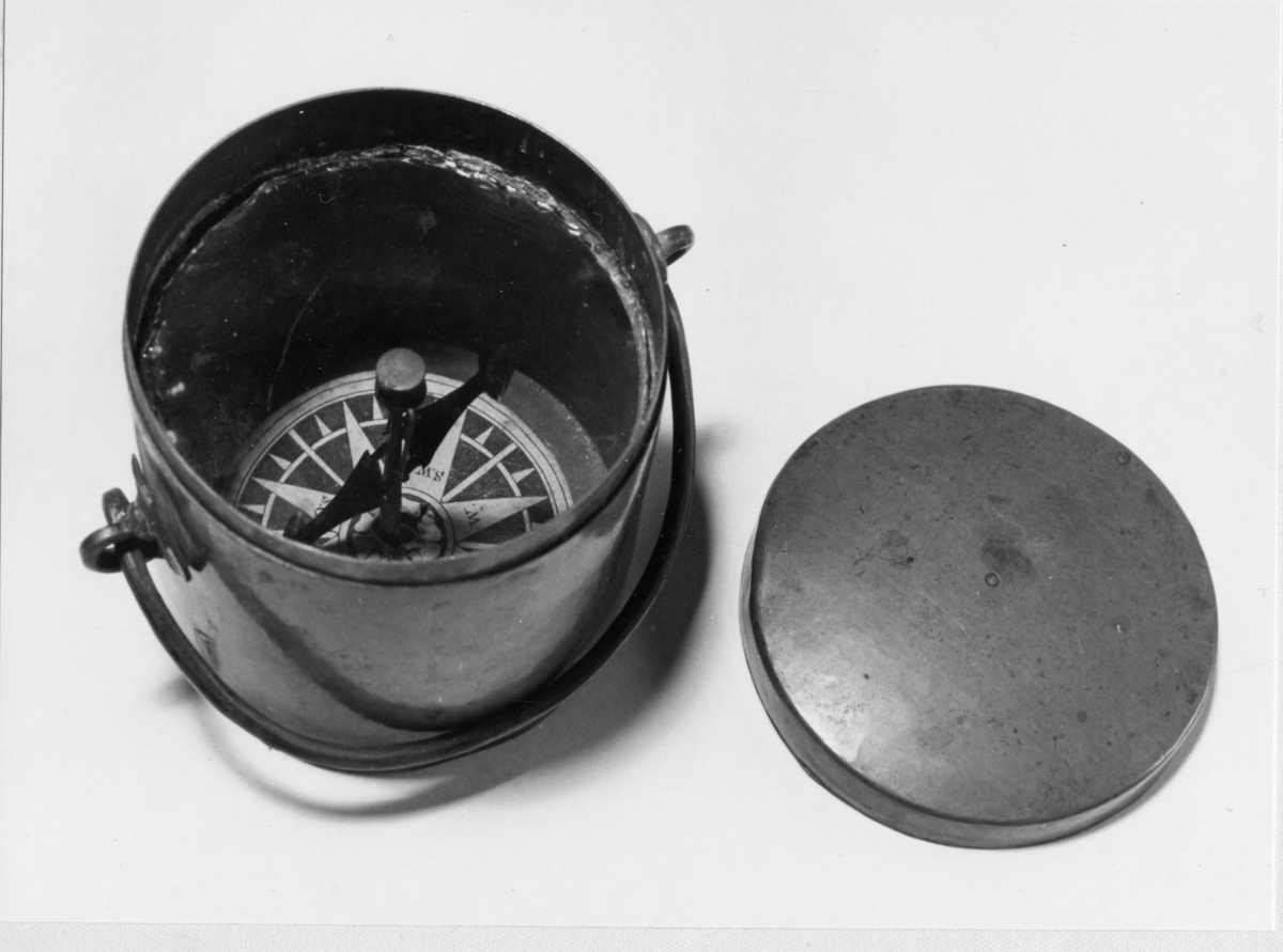 Luftkompass, gruvkompass, i cylindriskt kopparfodral med lock och handtag. Rosen tryckt och täckt med en glasskiva.