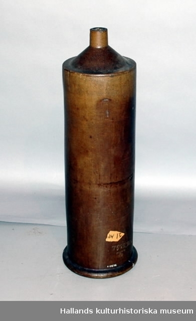 a) Trefotsstativ av järn. Svartfärgat. Upptill format för att passa en cylinder. Höjd 45,5 cm.b) Cylinder av keramik. Med avtappningsstrut i bottnen. Upptill en mjukt avrundad krage. Struten försedd med glasrör och gummislang med klämma. Höjd 77 cm, diameter 21 cm.c) Järnhätta med centrumhål. På hättan står tre S-formade elastiska hållare i järn.d) Platta av keramik. Perforerad. Stort centrumhål med krage. Diameter 19 cm, tjocklek 1 cm. 3 cm hög.e) Platta (sprucken) lika som d).
