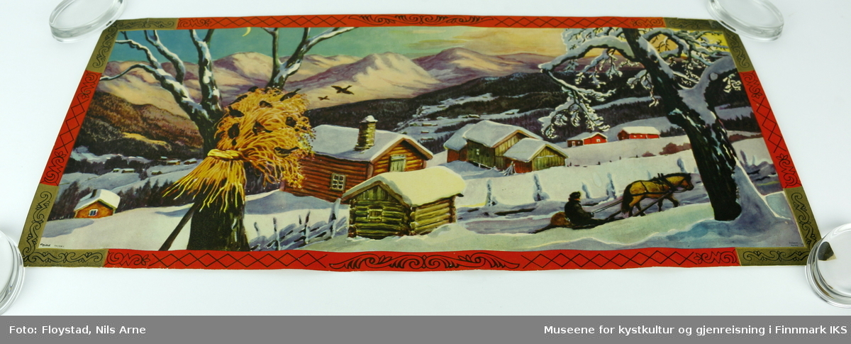 En rektangulær papirplakat med påtrykt vintermotiv av en snødekt fjellgård, et tre med julenek og fugler, en person med hest og slede. I bakgrunnen er det flere andre fjellgårder omgitt av skog og høye fjelltopper. Plakaten har en rød og gullfarget kant med mønsterdekor. Nederst i venstre hjørne står "Mittet 700/008 I", og i høyre hjørne står det "printed in Norway".