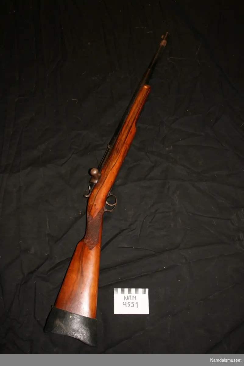 Harpungevær i original kasse av tre. Kassen inneholder gevær og harpuner m.m. Våpenet er et Kongsberg Harpun og redningsgevær modell 28, og er en videreutvikling av Jarmannriflen. Kaliberet er 10,15 x 61R-Jarmann.

Kolbekappen er av svart gummi og kolbehalsen er dekorert med utsåret rutemønster