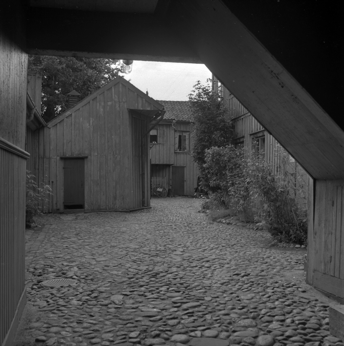 Stenbelagd innergård i Jönköping. Bilden tagen från porten och runt gården syns blomrabatter.