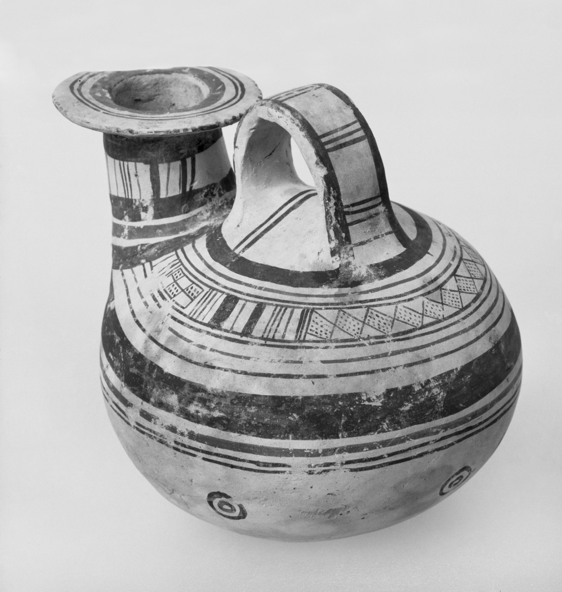 Askos
Ashos med dekor av lineære mønster i sort og mørkerødt. Tilhører den s.k. "daúnishe" vasegruppe som hører hjemme i Apúlía og som vesentlig stammer fra 7. og 6. f.kr. - H. til topp av hank: 11,7 cm., L. 11,8 cm