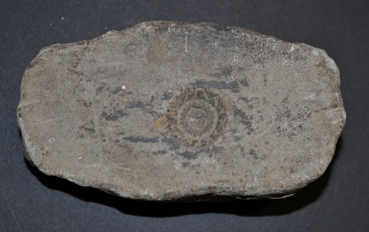 En sten med en hålighet i som är mönstrad och cirkelformad. Diameter på formen är 1,7 cm.