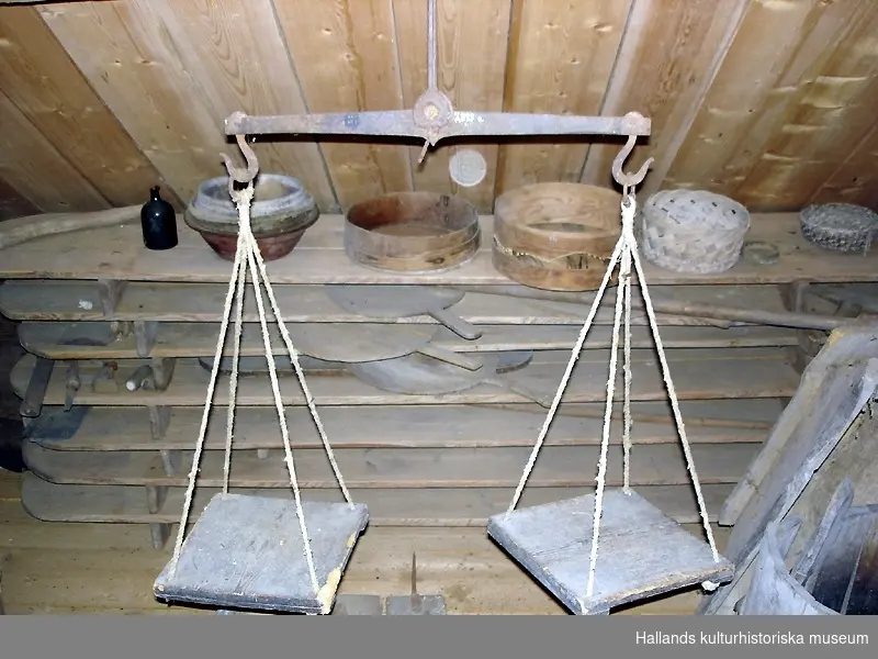 Våg i trä och järn med tillhörande plattor att hänga på vågen och ställa vikter på samt tillhörande vikter. Måttet på plattorna (a-b) är 270mm x 26mm. De är märkta NHH 1100 i botten. Mått och beskrivning på d-f:d: vikt i järn, 10 kg? D 90mm, H 160mm.e: "Pundare, 5 skålpund". Vikt i järn, 5 kg, tidigare märkt 1372. D 80mm, H 110mm.f:  "Pundare, 5 skålpund" Vikt i järn, 1 kg, Stämplar, oläsliga. D 50mm, H 70mm.