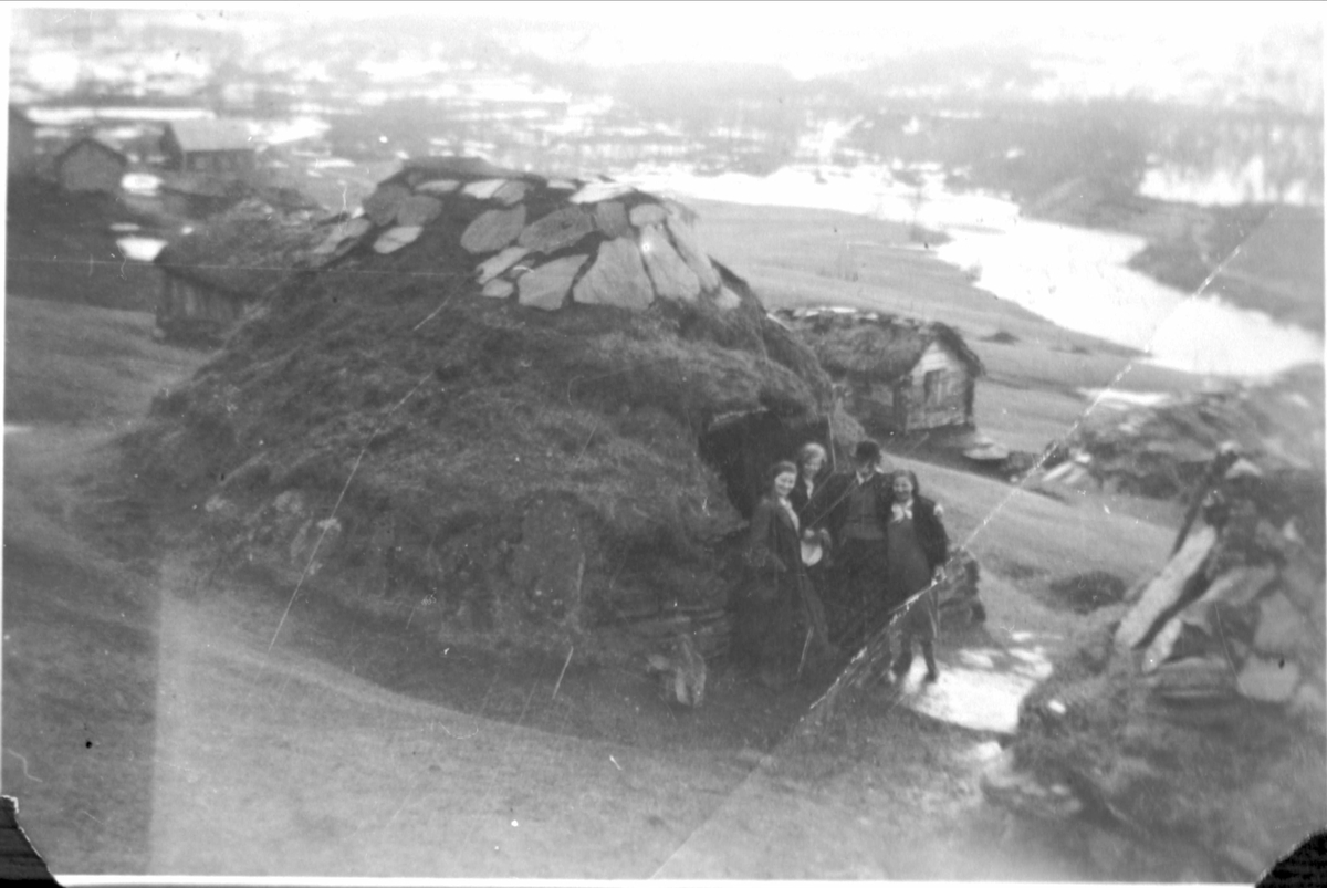 Fire personer stående utenfor jordgamme ved Saltvann i Grovfjord.