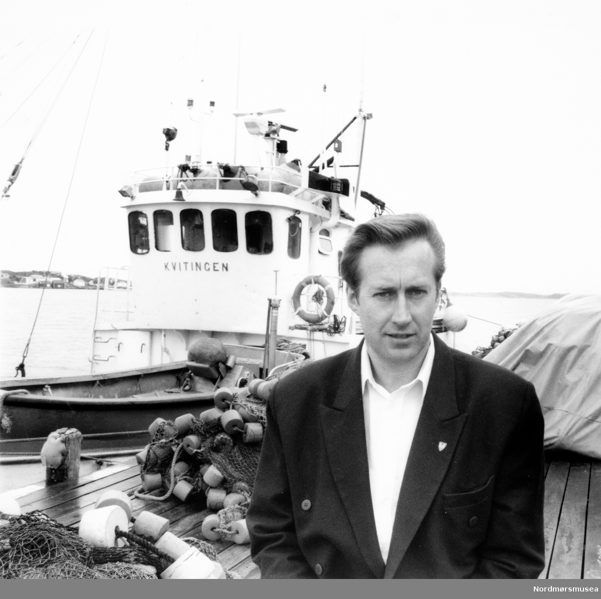 Leif Helge Konshaug foran fiskebåten Kvitingen. 
		Bildet er fra avisa Tidens Krav sitt arkiv i tidsrommet 1970-1994. Nå i Nordmøre museums fotosamling.