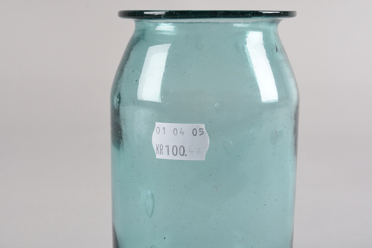 Sylindrisk støypt glaskrukke. Korpus svingar inn mot toppen og deretter ut til ein krage ved munningsranda. Glaset er produsert av resirkulert glas og har fleire luftboblar i godset. Lett grønfarga.