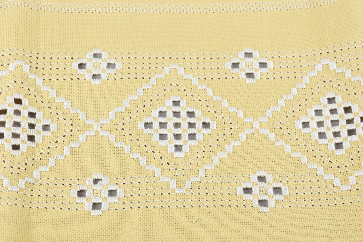 Avlang bordløpar i hardangersaum, brodert på Aida tekstil/bomull, med motiv på midten og dekorkant rundt.