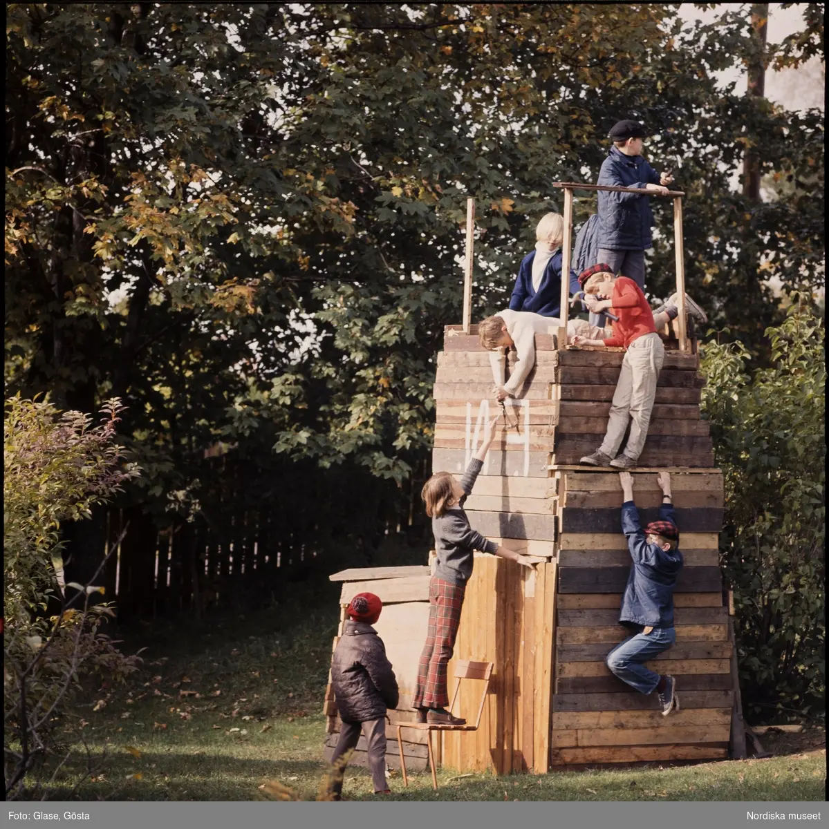Barn bygger ett torn i trä att klättra i.