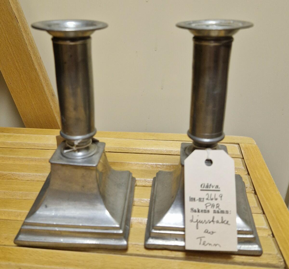 "Ljusstake, par av tenn, som skissen, med fyrkantig, utsvängd fot överdelen cylindrisk lös ljuspipa upptill med utvikt mynningsrand. - Höjd 15 cm. Foten 8,5 x 8,5 cm. Mynningsdiam. 4,8 cm. - Fr. Vifstavarv. - Gåva av E F Engelstedt, Sundsvall." (skiss) (ur lappkatalogen, Arvid Enqvist 1936)

Inv. bok II:

