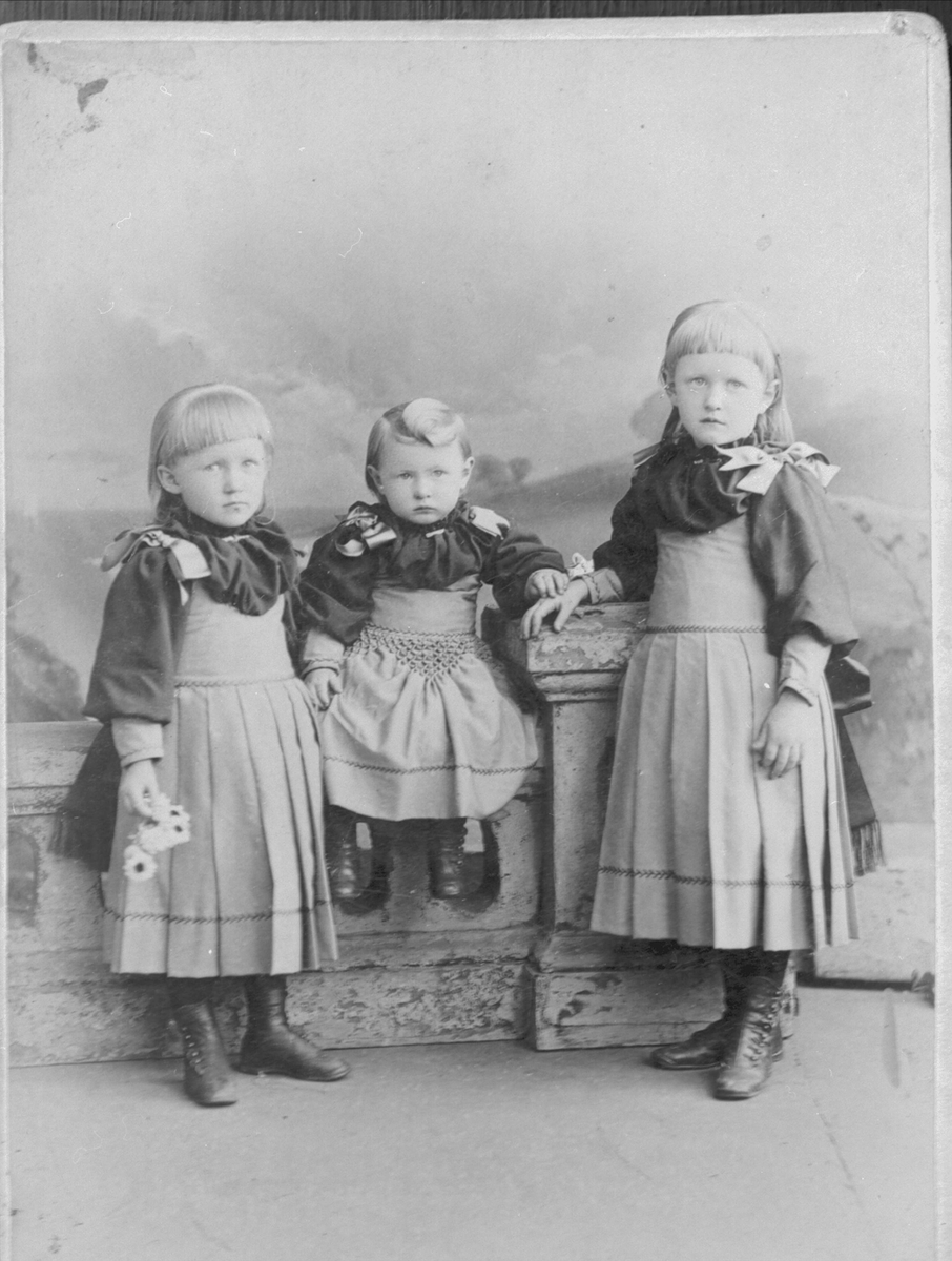 Studioportrett av tre små piker i helfigur. Bildet er tatt i USA.