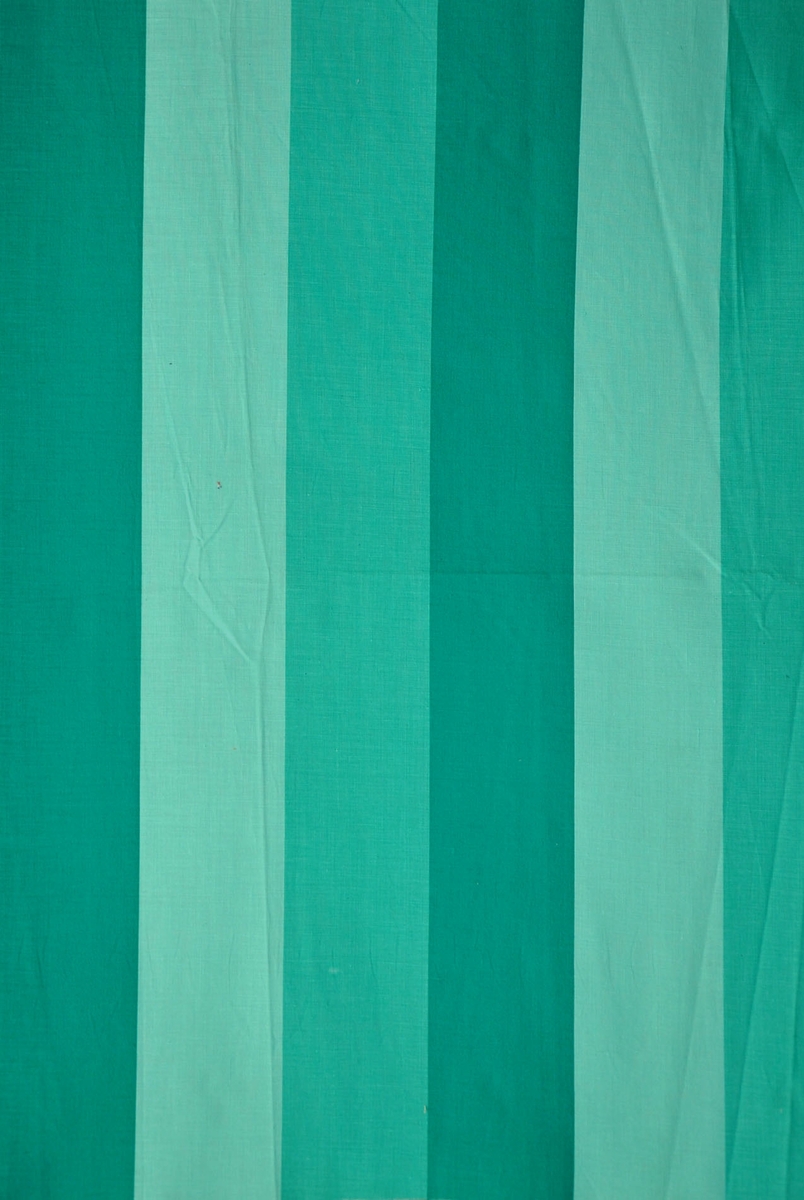 Bomullstyg, 1960-talet.
Beklädnadstyg på 90 cm bredd, randigt mönster i olika gröna nyanser.
Otvinnat garn.
Krafig appretur.